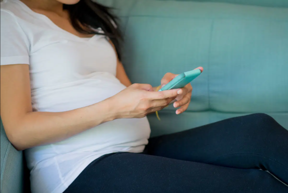 Pregnany lady sat using her mobile phone