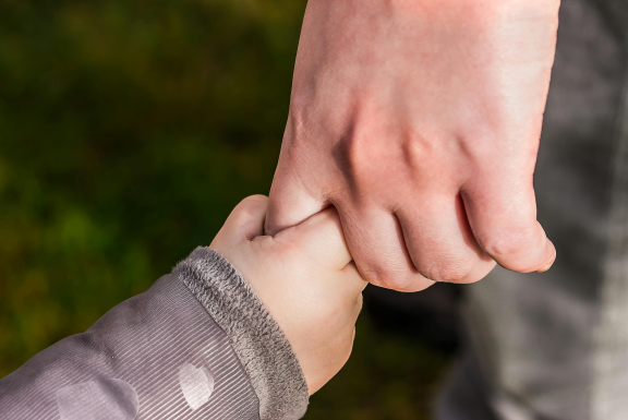 Adult male hand holding a young child's hand